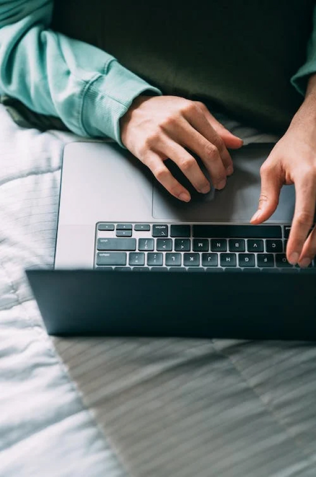 Close-up of a person's hands typing on a laptop keyboard, suggesting work, communication, or internet browsing, with a focus on the interaction between user and device.