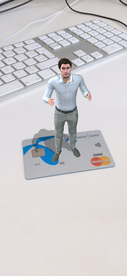 An augmented reality (AR) depiction of a small, animated figure of a man standing on top of a credit card, next to a keyboard, indicating a visualization of personal finance and an online banking services.